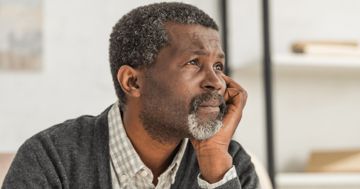 Depressed, senior african american man holding hand near face