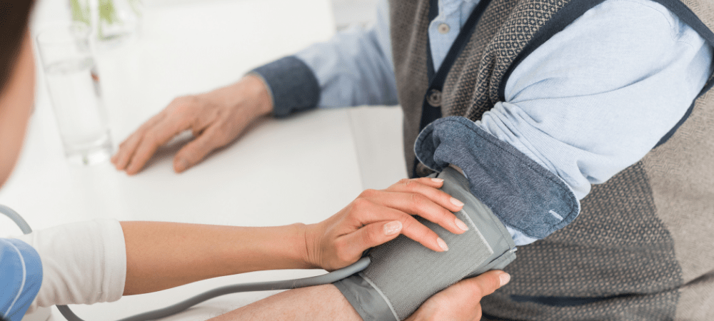 Cropped view of nurse putting hands on grey haired man, measuring blood pressure