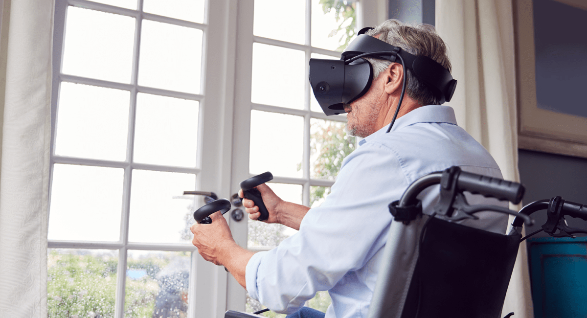 Mature Disabled Man In Wheelchair At Home Wearing Virtual Reality