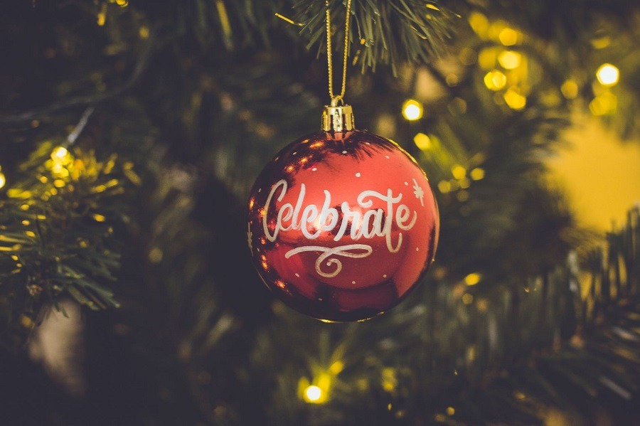 Christmas ornament with the word "celebrate" hanging in tree