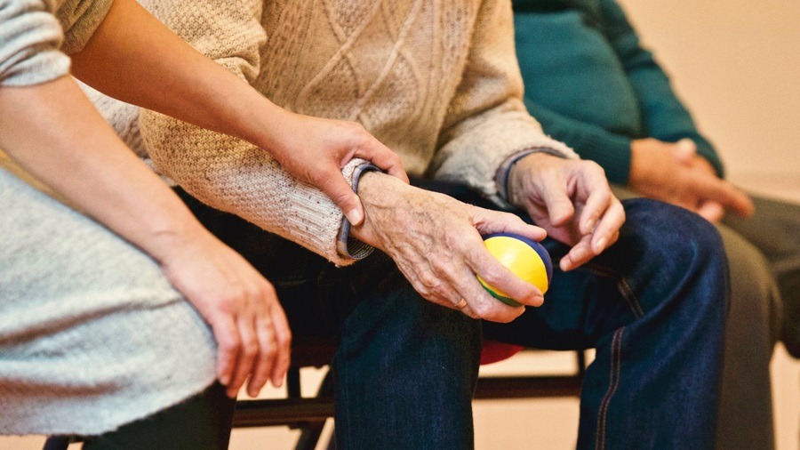 Elderly man receives help while completing hand exercises