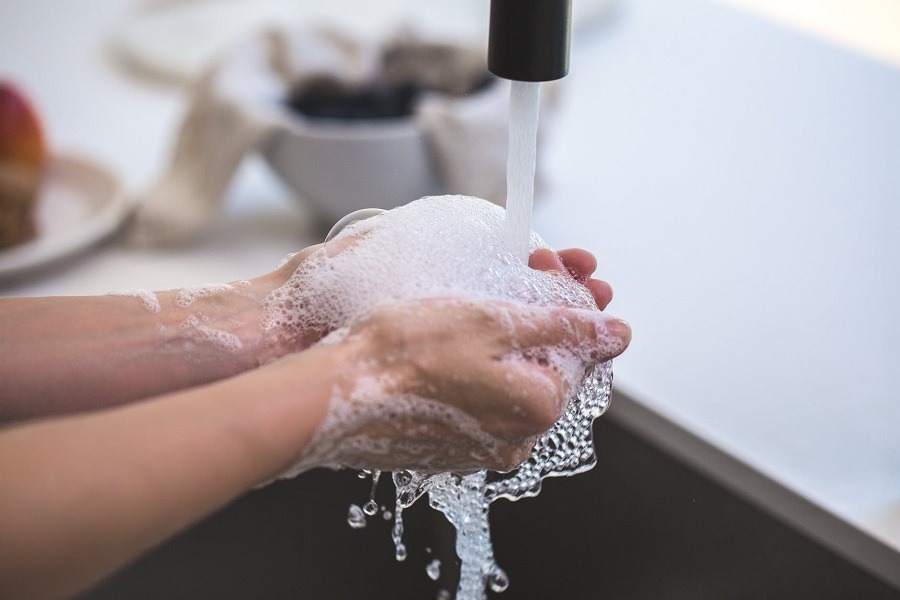 Person washing hands in sink with soap and water