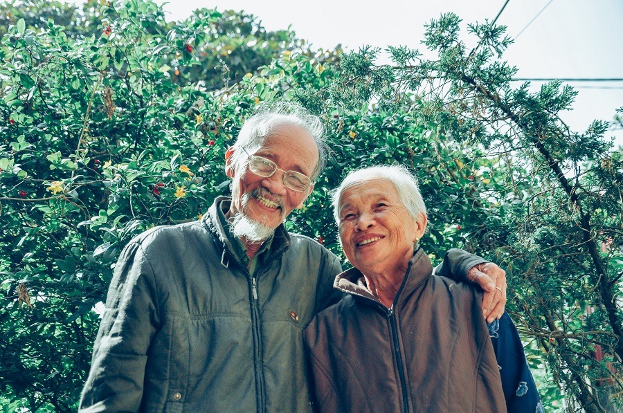 Elderly man and women pose together outside