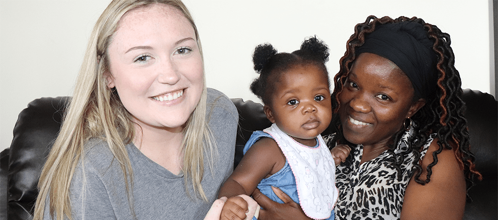 Volunteer Brooke posing with a client and her daughter