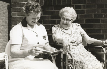 Sepia photo of a PSW reading to her elderly client