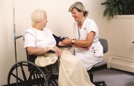 Nurse taking the blood pressure of her wheelchair-bound patient