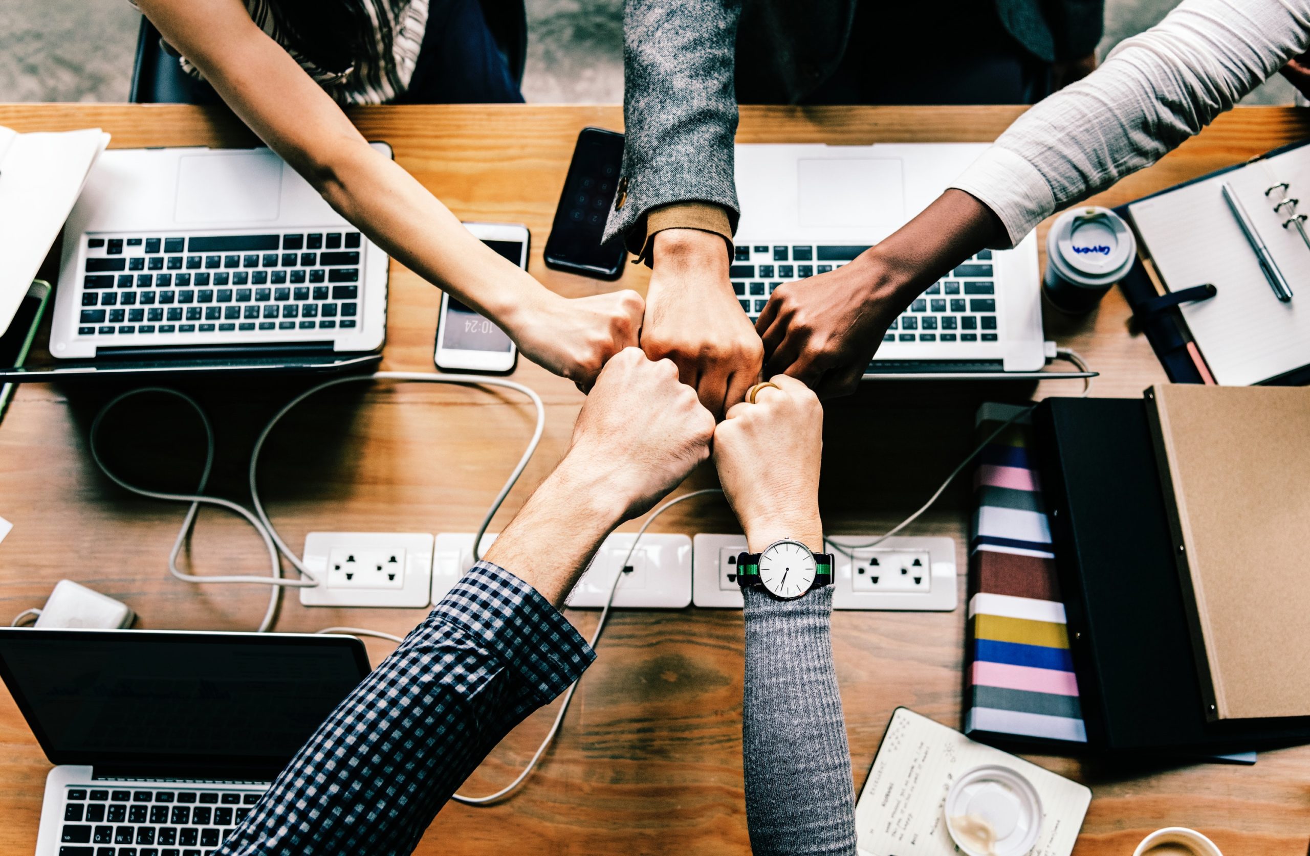 Hand fist bumping overtop of computers