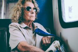 Elderly woman wearing sunglasses on public transit