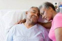 Elderly woman with her husband, who is in a hospital bed