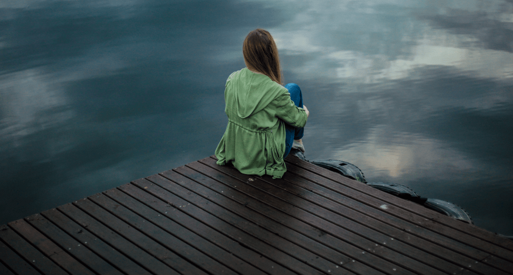 Women sitting on dock near lake