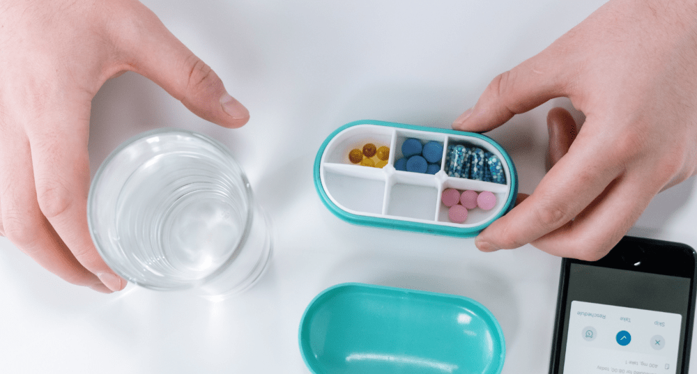 Person about to take pills from their pill box after being reminded by cell phone