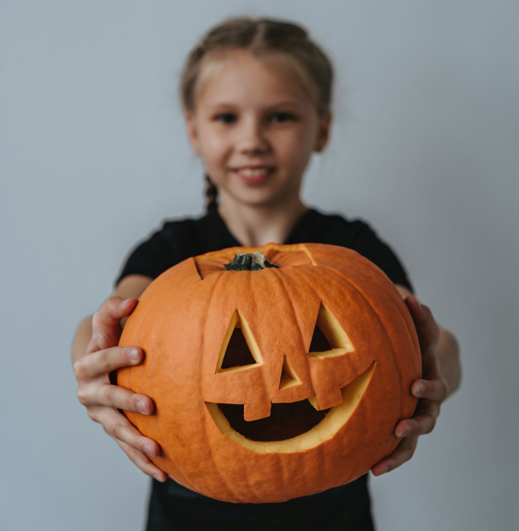 Child holding a carved pumpkin
