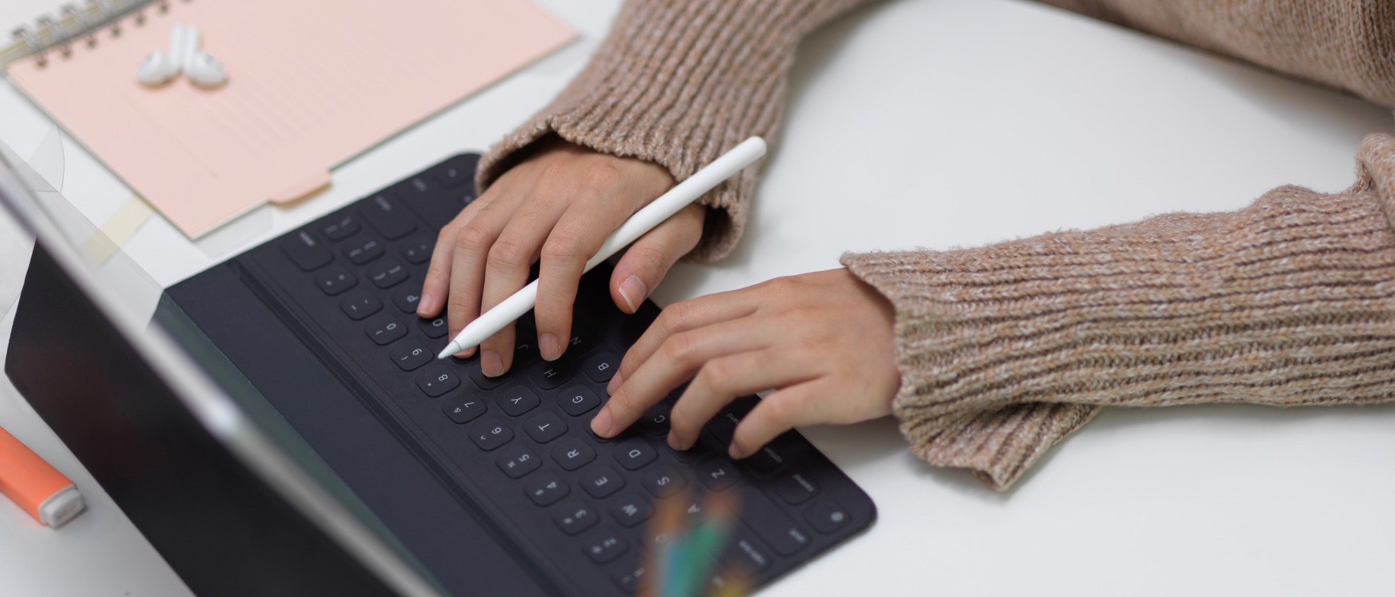 Cropped shot of female typing on tablet keyboard while holding stylus pen on office desk