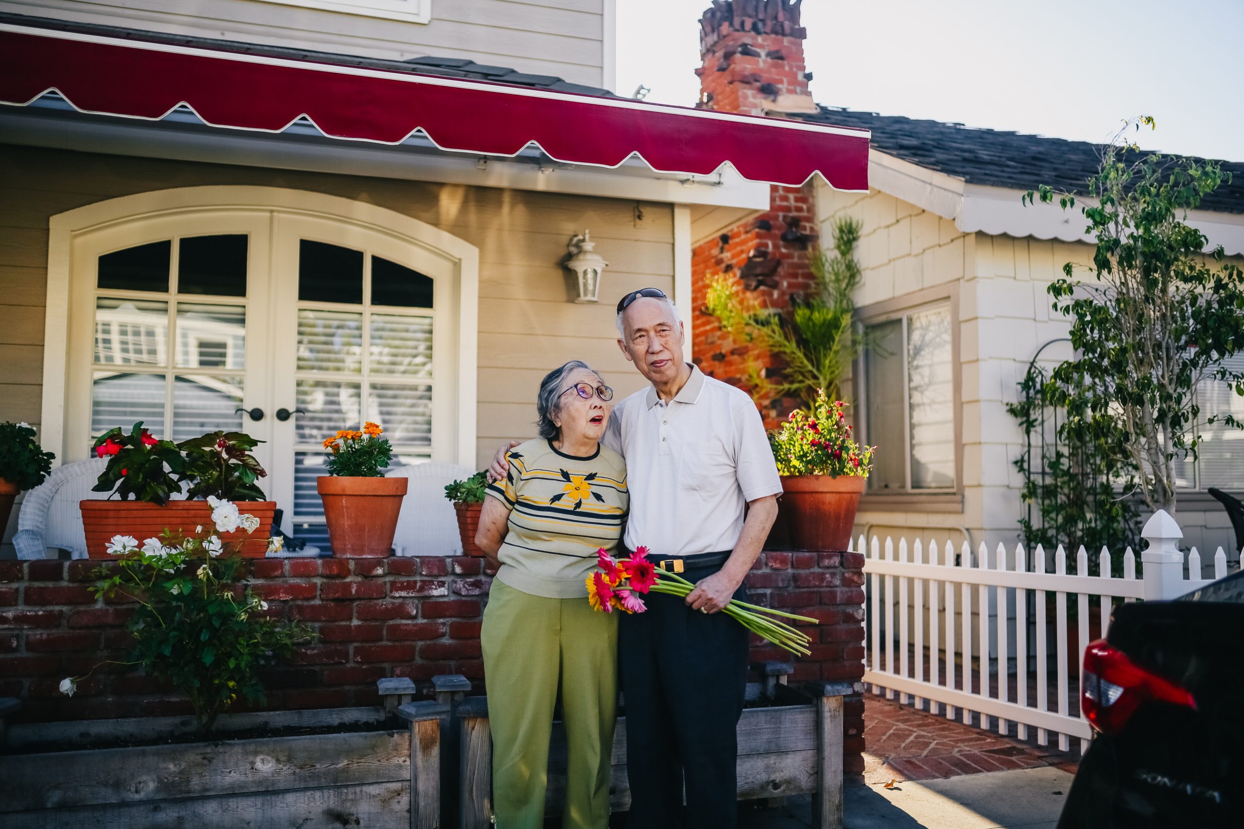Elderly couple gardening in front of their home