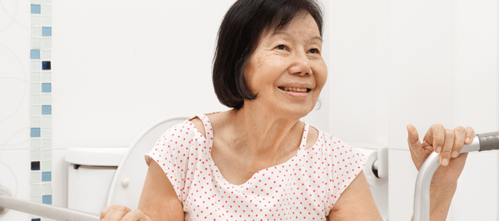 Women sits on toilet with support aids