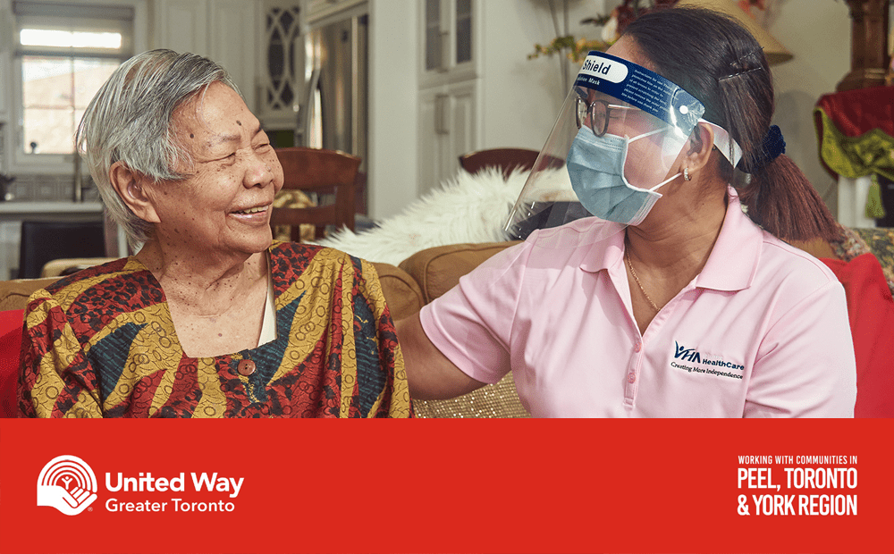 VHA PSW sits beside her client while wearing a mask and shield during the COVID-19 pandemic