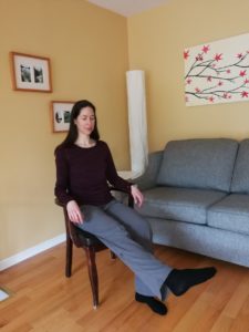 Woman in a chair with her leg lifted off the ground, foot pointed outwards