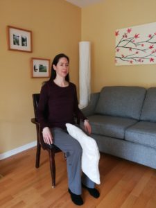 Woman sitting straight with a pillow between her knees