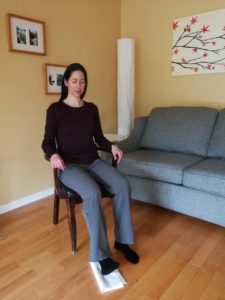 Woman sitting on a chair with one foot positioned in front of the other