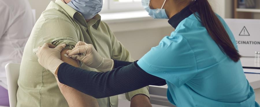 Nurse administering a vaccination to an elderly man