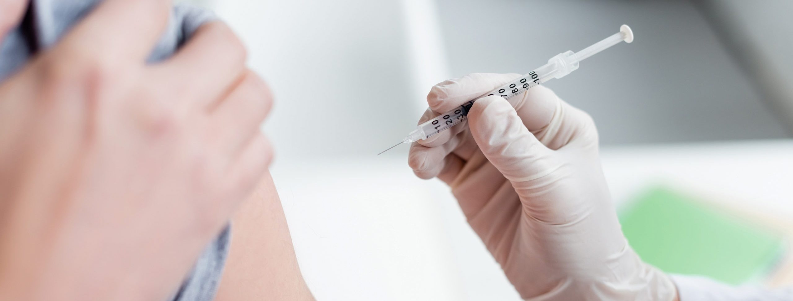 Cropped view of doctor in latex gloves holding syringe near patient