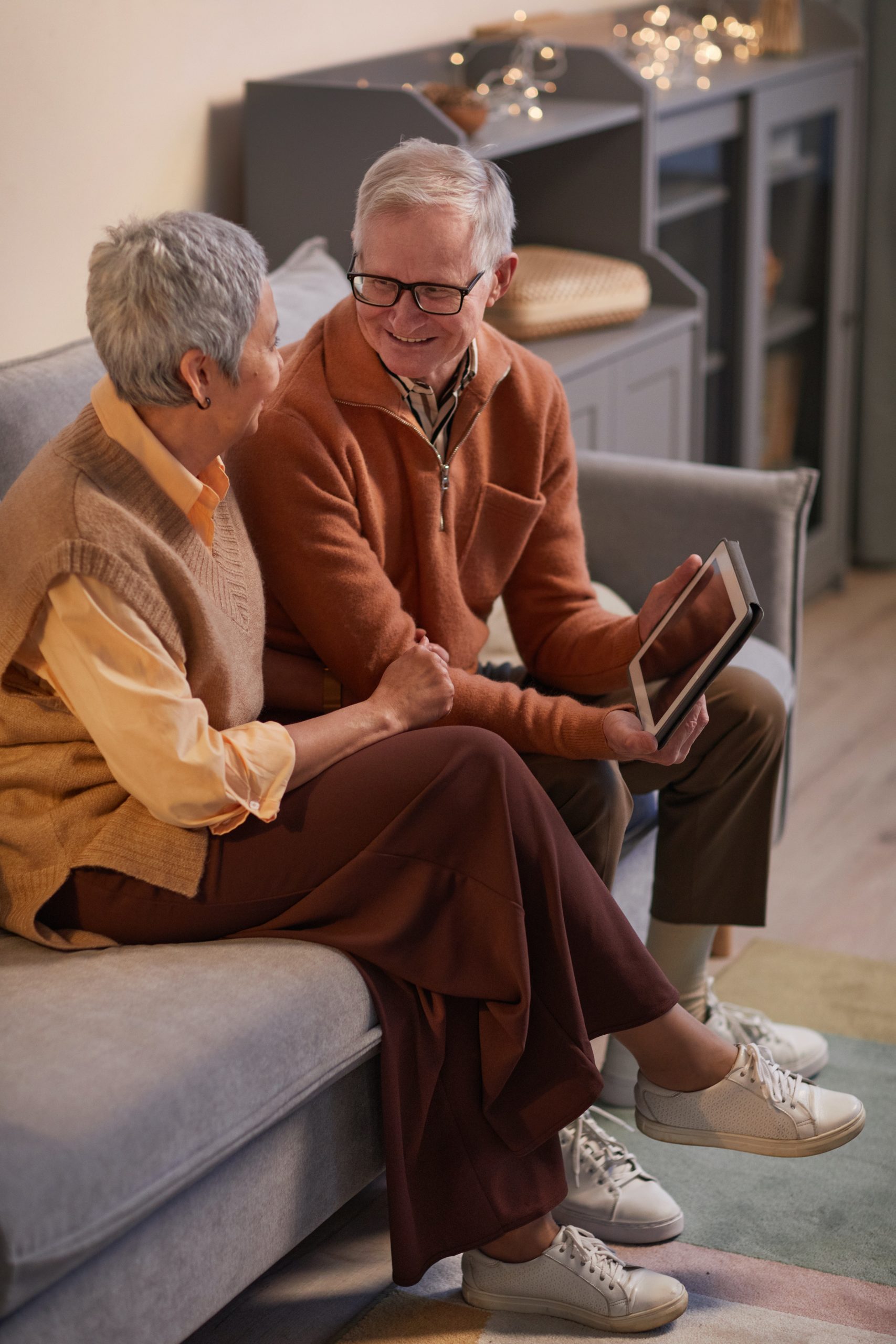 Elder couple sitting on a couch, smiling, laughing