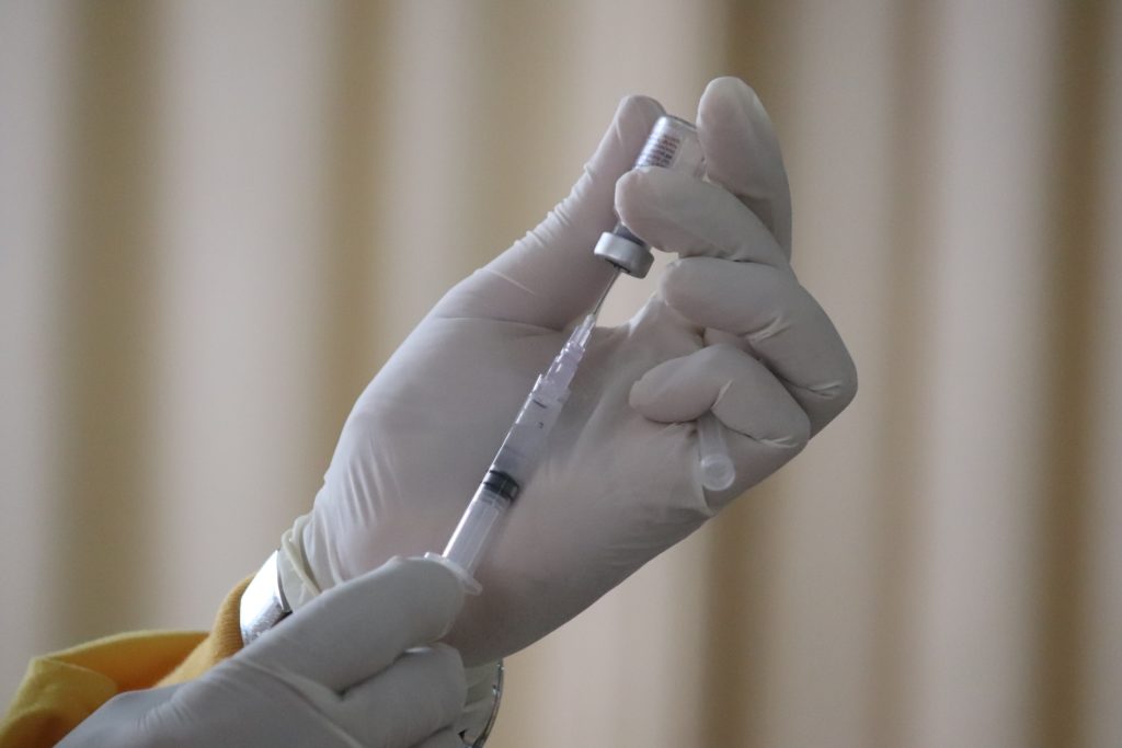 Gloved hand drawing a vaccine from a vial