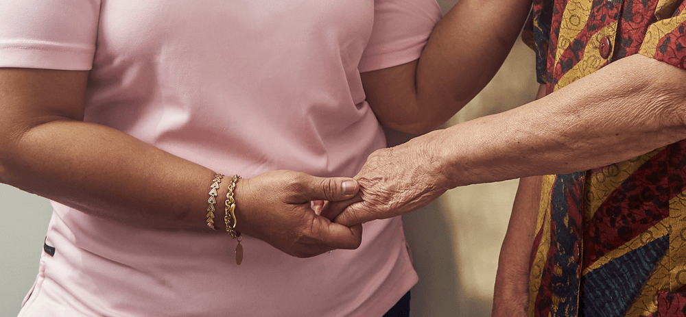 A VHA Personal Support Worker holds a client's hand