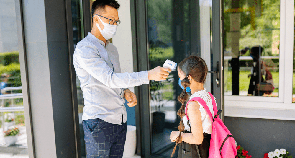 Teacher checks a student's temperature before class