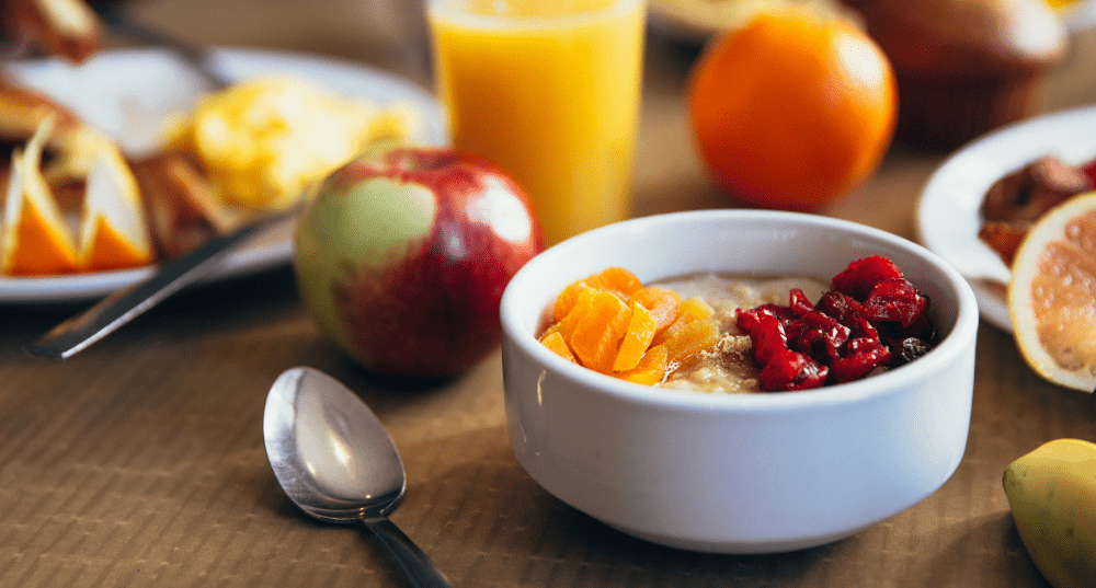 Bowl of oatmeal for breakfast with a glass of orange juice and an apple in the background