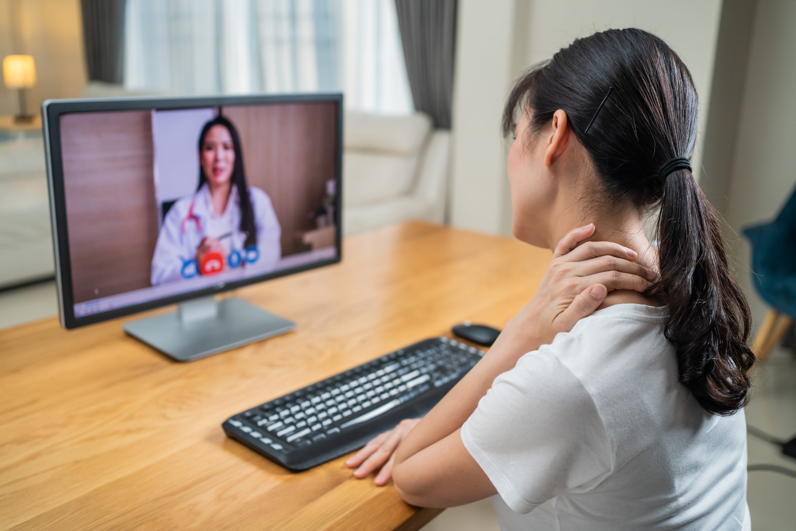 Asian woman consult with online doctor for medical healthcare in house. Freelance girl worker patient work at home due to Covid 19 crisis talk to Therapist on virtual telemedicine video call on screen