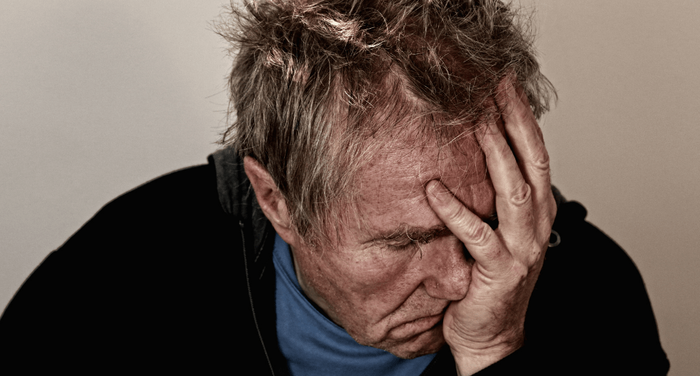 Man with headache holds his head in his hand