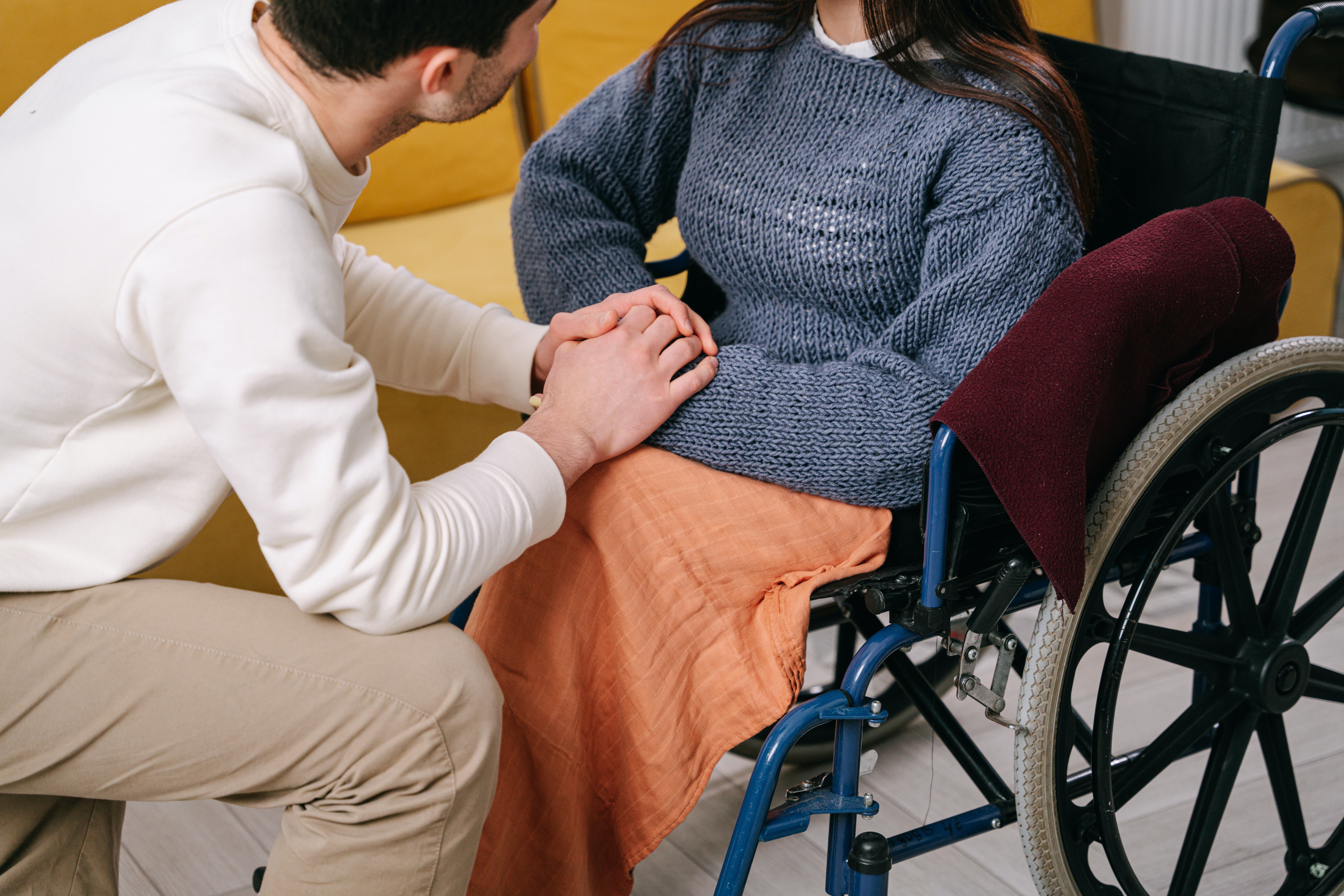A caregiver shows his support to a woman in wheelchair