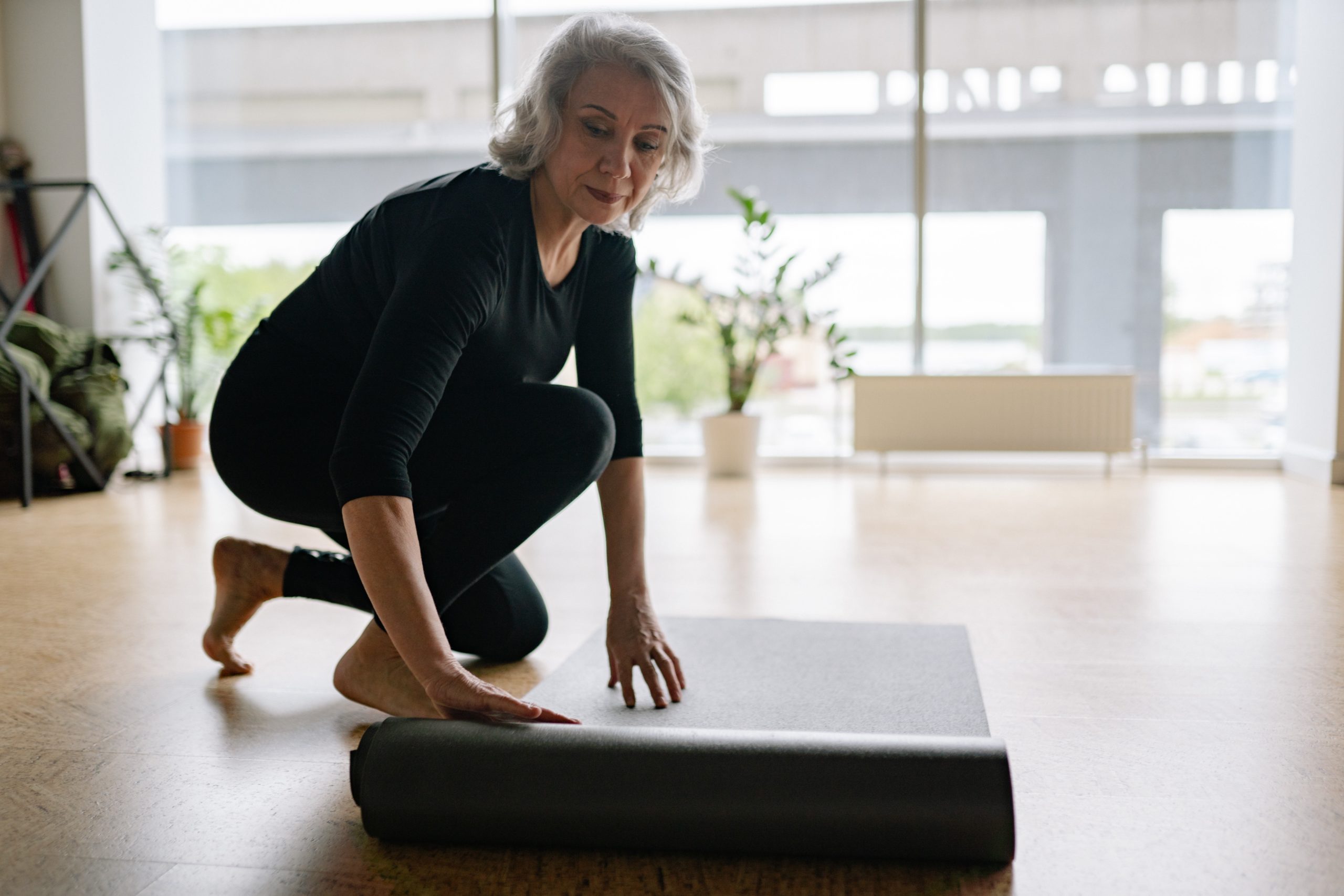 Older woman rolling out exercise mat