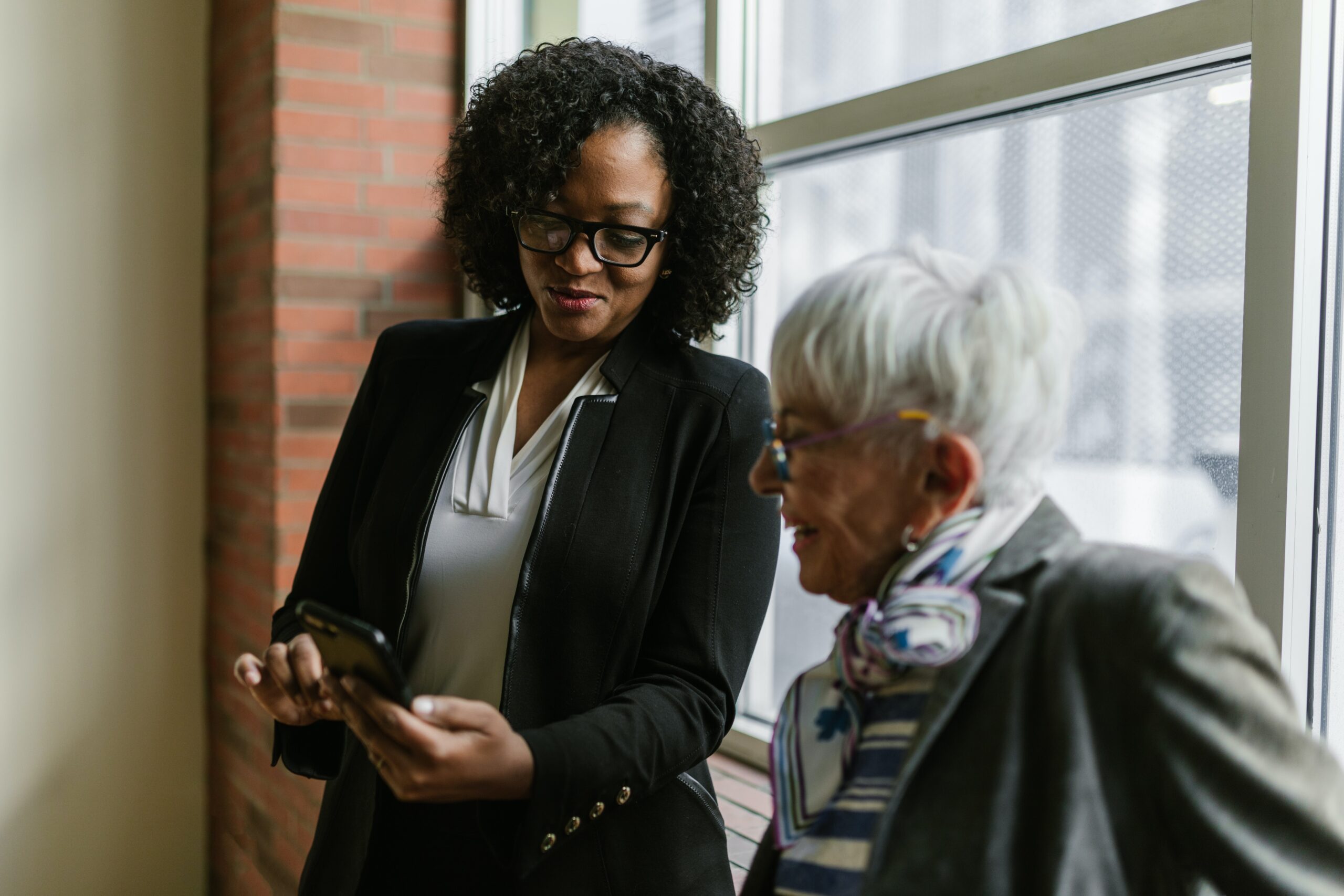 Woman teaching mother how to access something on cellphone