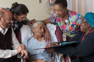 A family and care providers around a patient in a hospital bed.