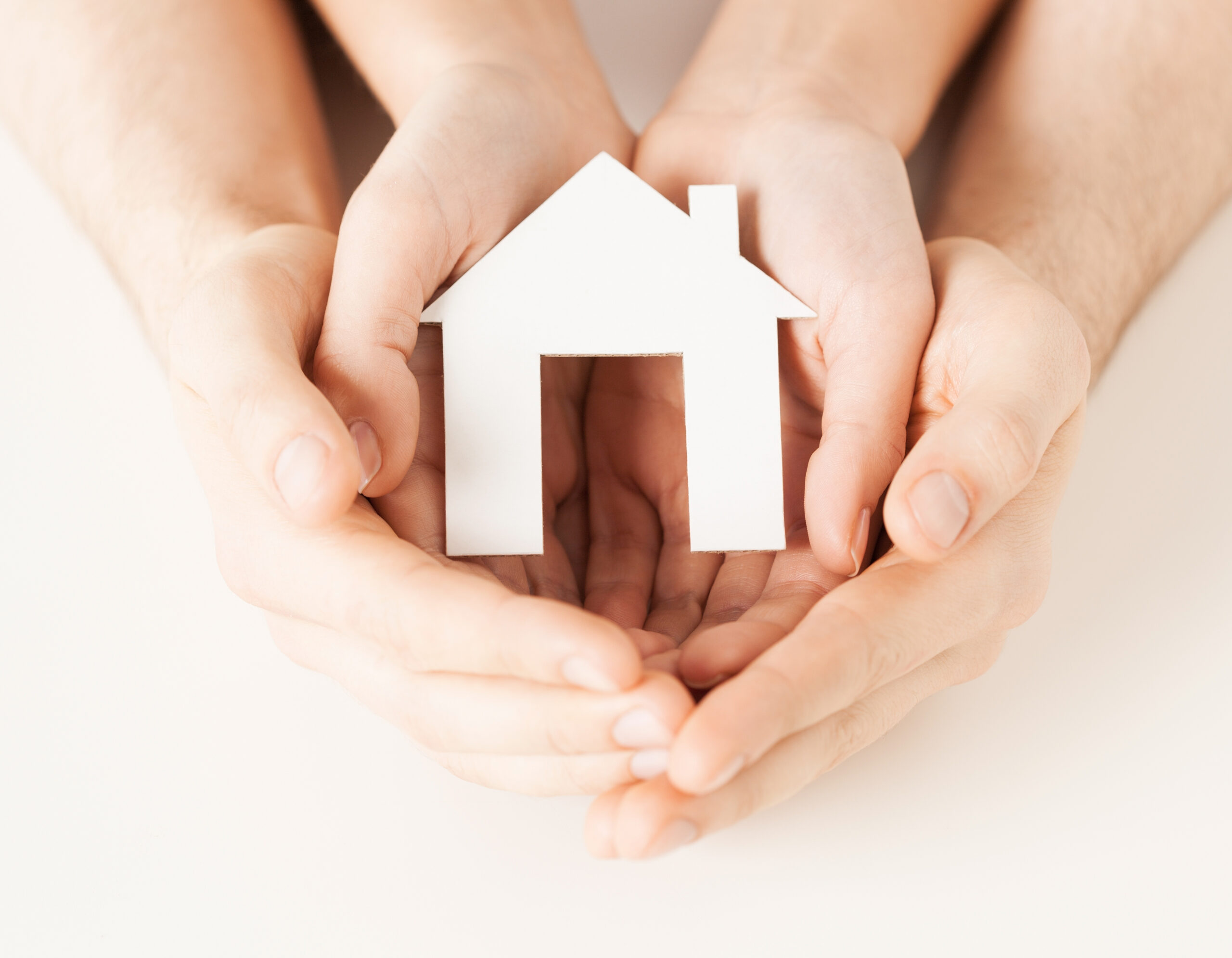 picture of man and woman hands holding paper house