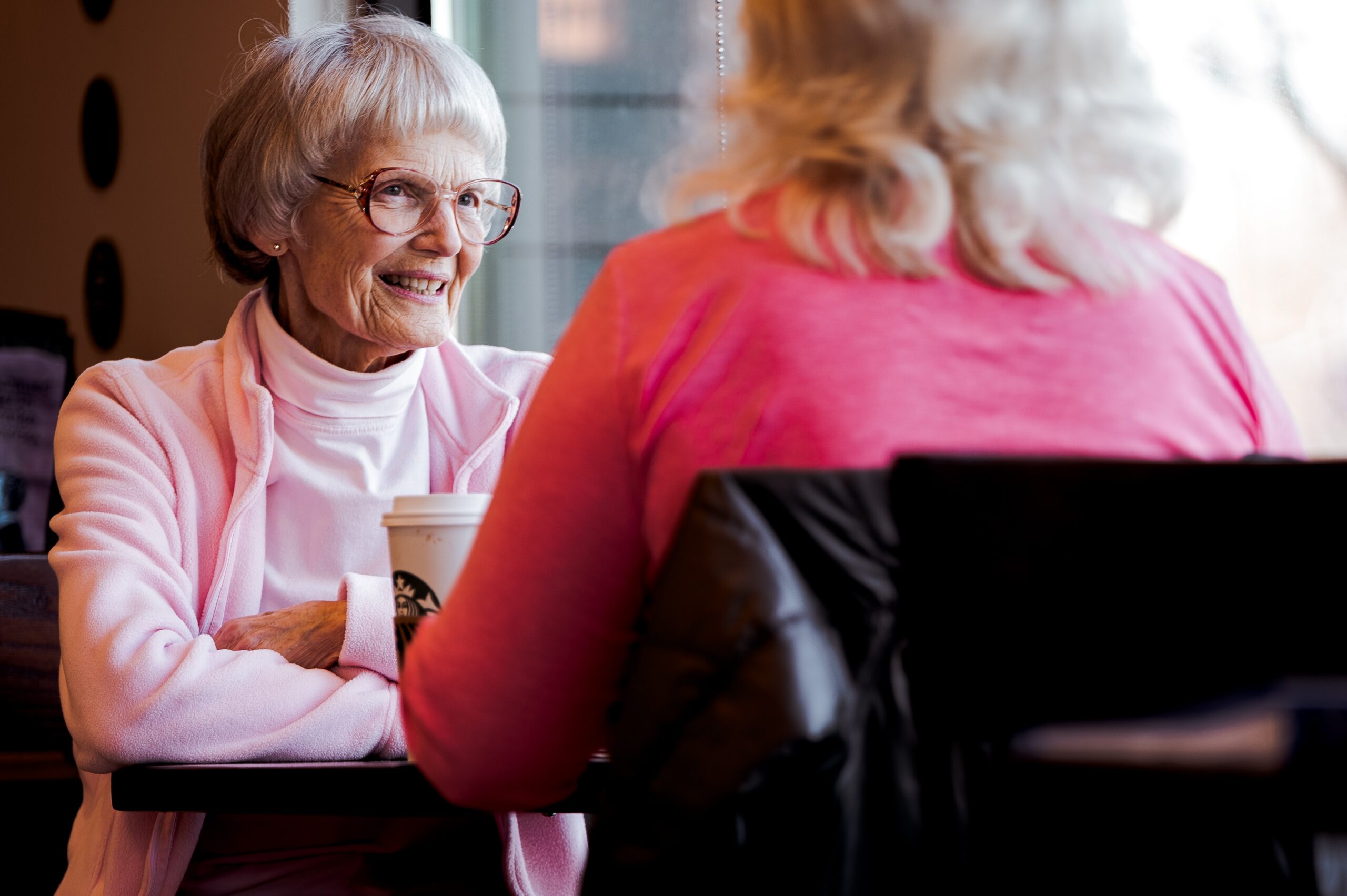 Two older women drinking coffee together