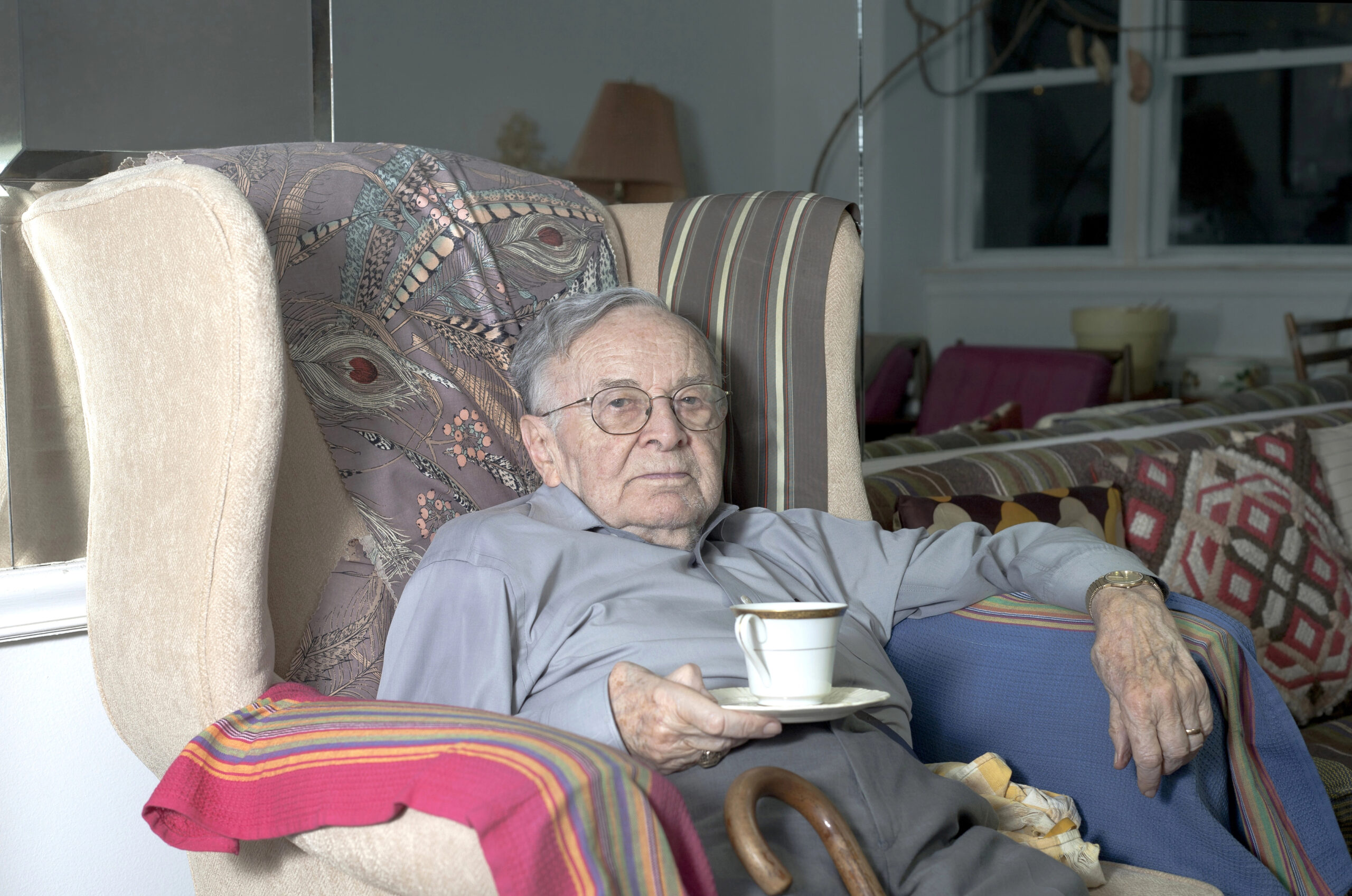 Older adult male sitting in a chair with a cup of tea.