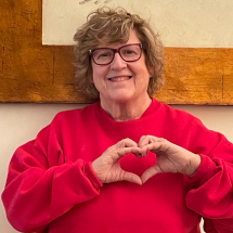 Client partner Sonya poses in front of wall, her hands in the shape of a heart.