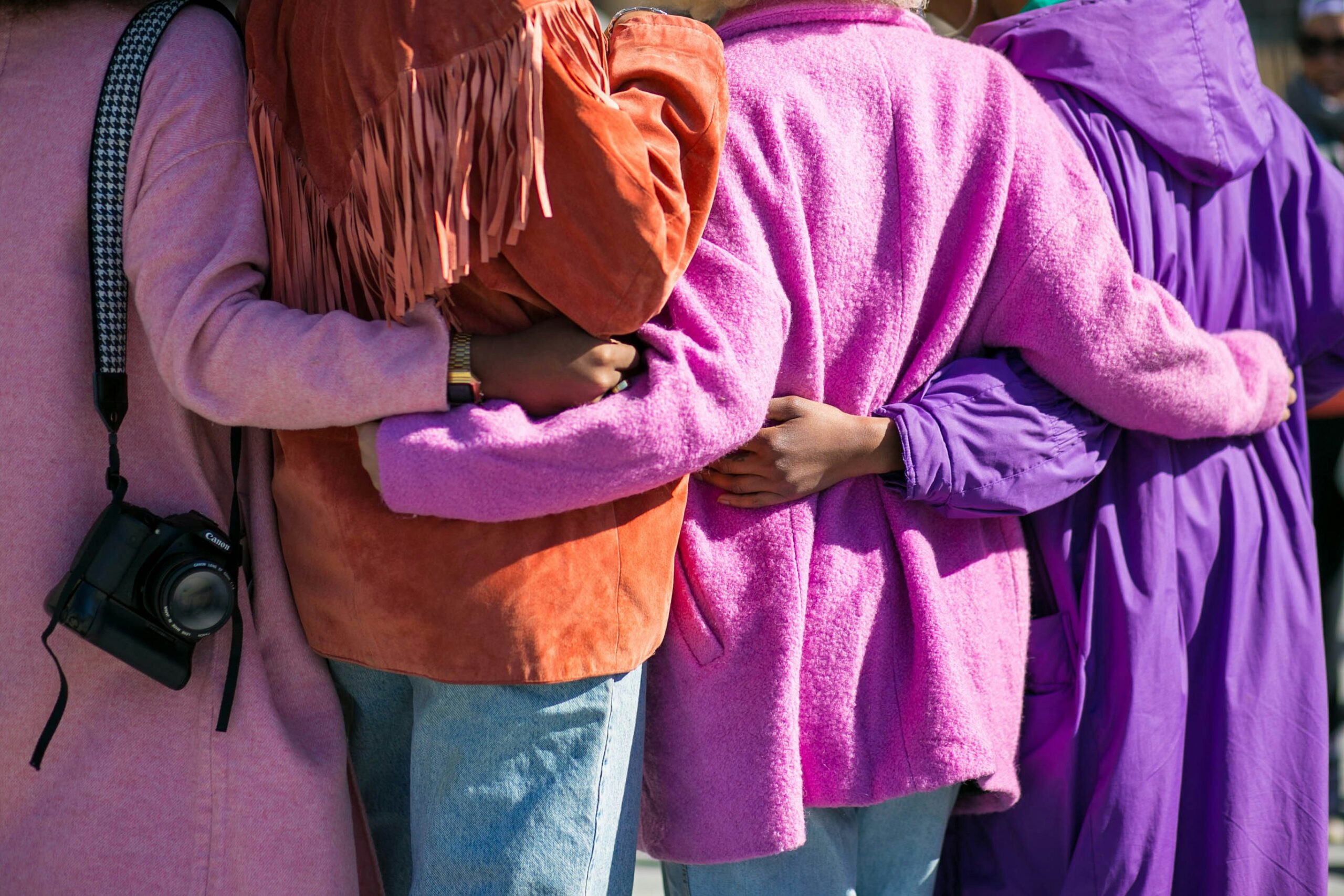 Four person holding each others waist at daytime