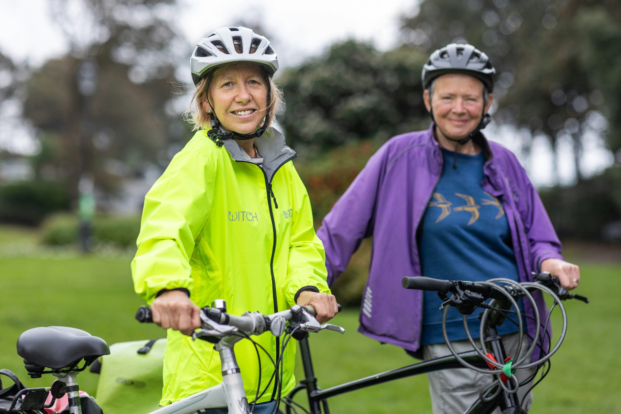 Two older women riding a bike with helmets