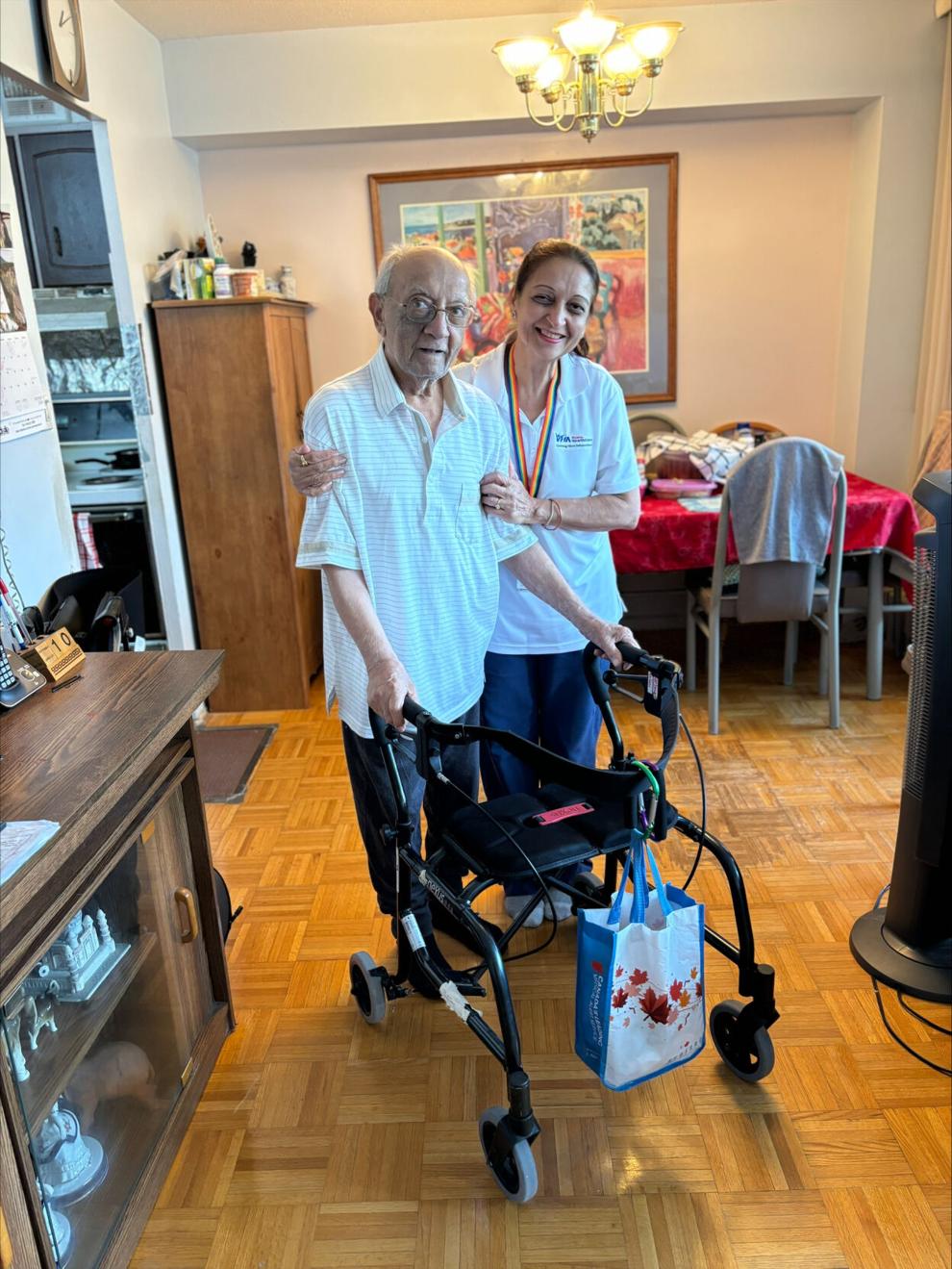 A PSW and client with a walker pose together in an apartment.