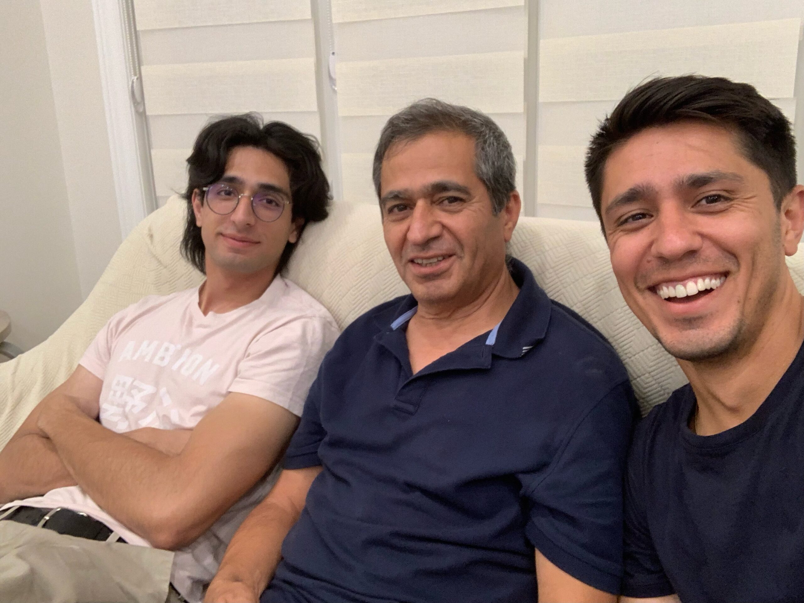 Sami Bharat sitting in the middle of a couch with each of his sons sitting with him.