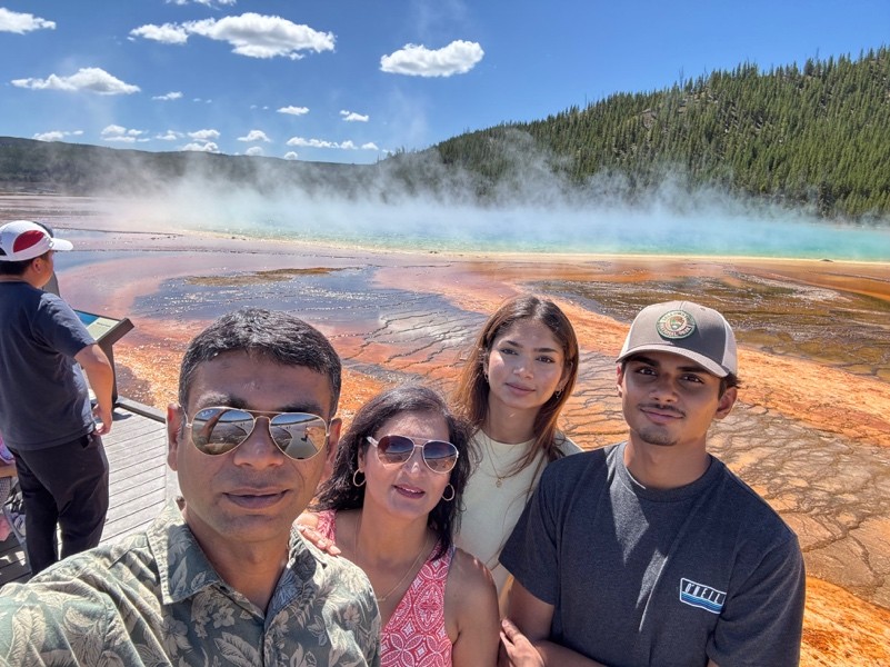 Chirag Patel and his family standing in front of a steaming hot spring