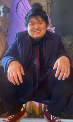 Haichen Liu crouched down and smiling at the camera.