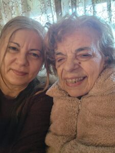 Helen and her mother, Irene, sit closely with their heads touching and smiling warmly. 