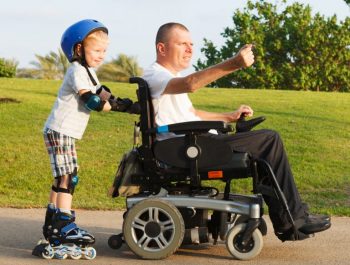 Man in electric wheelchair with his son roller skating beside him